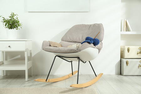 Skein of soft yarn, crochet hook and knitting sample on armchair indoorsの写真素材