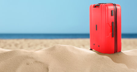 One red suitcase on sandy beach near sea. Banner design with space for textの写真素材