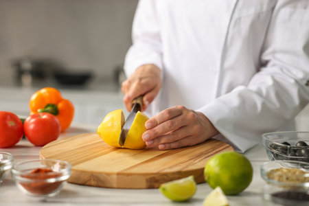 Professional chef cutting lemon at table in kitchen, closeupの写真素材