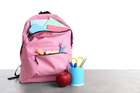 Backpack with different school stationery and apple on gray textured table against white background, space for textの写真素材