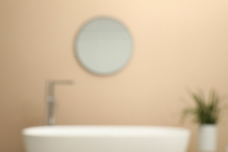 Blurred view of bathtub, houseplant and mirror in bathroomの写真素材