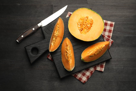 Fresh ripe Cantaloupe melon and knife on dark wooden table, flat layの写真素材