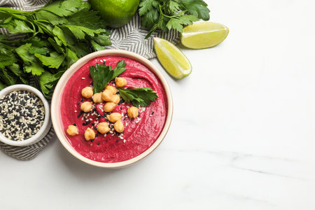 Tasty beetroot hummus in bowl and products on white marble table, flat lay. Space for textの写真素材