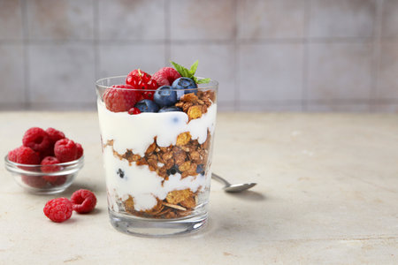 Tasty yogurt with fresh berries, granola and mint in glass on gray textured table, space for textの写真素材
