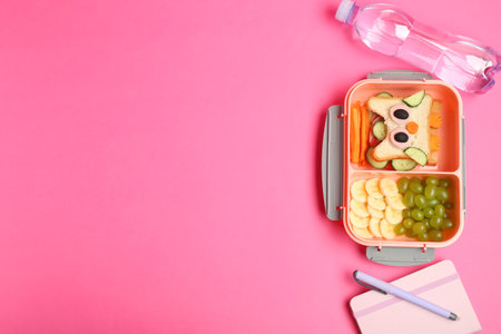 Lunch box with snacks, bottle of water and stationery on pink background, flat lay. Space for textの写真素材