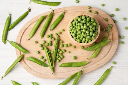 Fresh green peas and pods on white wooden table, flat layの写真素材