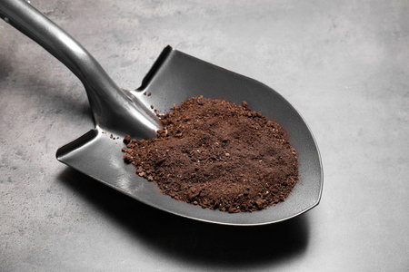 Metal shovel with soil on grey tableの写真素材
