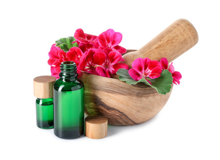 Geranium essential oil in bottles, beautiful flowers, mortar and pestle isolated on whiteの写真素材