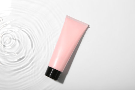 Cosmetic product. Tube with cream in water on light background, top viewの写真素材