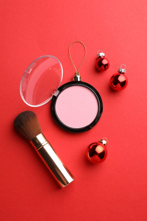 Blusher in shape of Christmas ball and brush on red background, flat layの写真素材