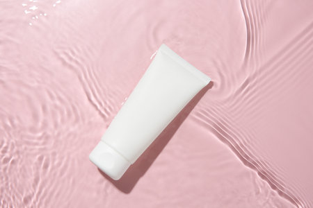 Cosmetic product. Tube with cream in water on pink background, top viewの写真素材