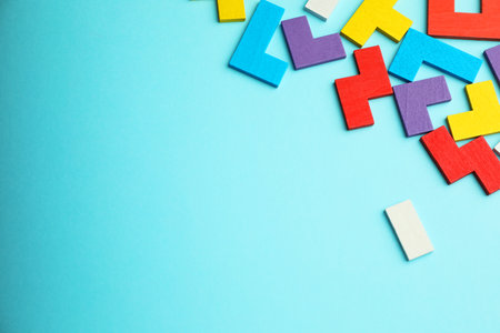 Colorful wooden puzzle pieces on light blue background, top view. Space for textの写真素材