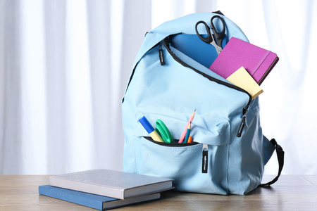 Backpack with different school stationery on wooden tableの写真素材