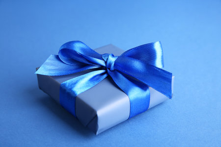 Gift box with satin bow on blue background, closeupの写真素材