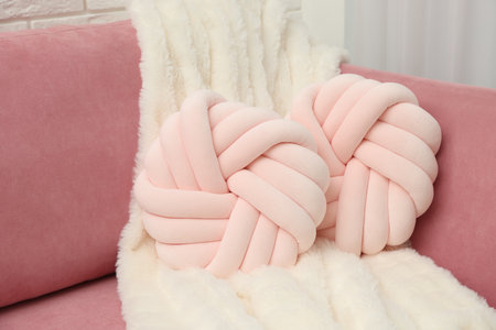 Decorative pillows and fluffy blanket on pink sofa indoorsの写真素材