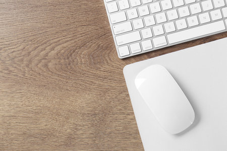 Computer mouse with mousepad and keyboard on wooden table, flat lay. Space for text