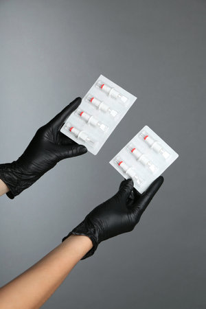 Professional cosmetologist holding disposable cartridge systems for permanent makeup on grey...