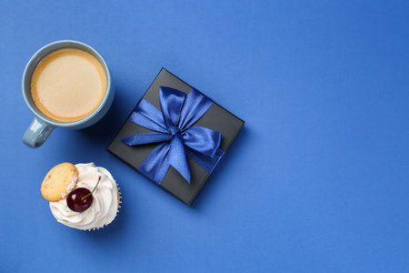 Happy Father's Day. Gift box, cupcake and cup with coffee on blue background, flat lay. Space for textの写真素材