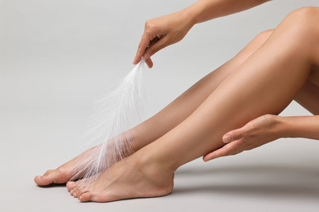 Woman with smooth legs and feather on grey background, closeupの写真素材