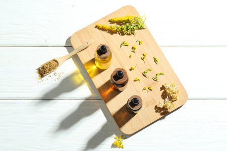 Tinctures in bottles, goldenrods and helichrysum flowers on white wooden table, top viewの写真素材