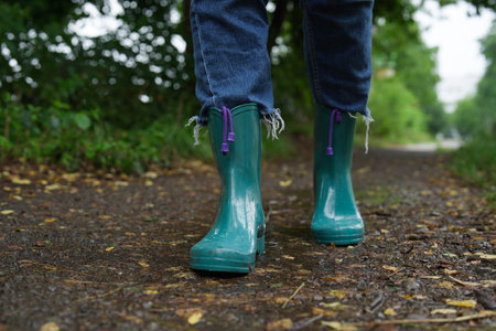 Woman in turquoise rubber boots walking on wet road, closeupの写真素材