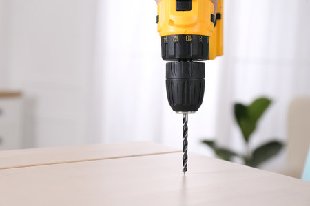 Woman with electric screwdriver assembling furniture at home, closeup. Space for textの写真素材