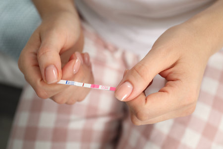 Woman holding negative pregnancy test indoors, closeup viewの写真素材