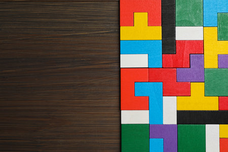 Colorful puzzle pieces on wooden table, top view. Space for text