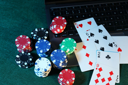 Online poker. Playing cards, chips and laptop on green table