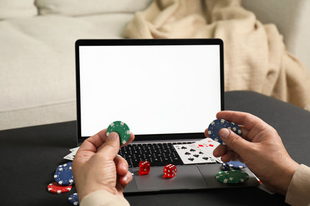 Man with laptop playing poker at black table, closeup. Online gameの写真素材