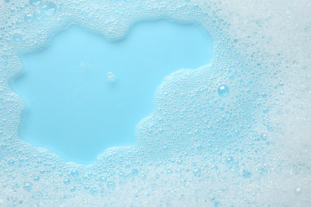 Washing laundry. White foam with bubbles on light blue background, top viewの写真素材