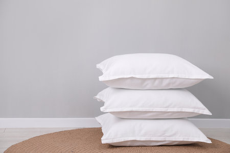 Stack of white pillows on floor indoors. Space for textの写真素材