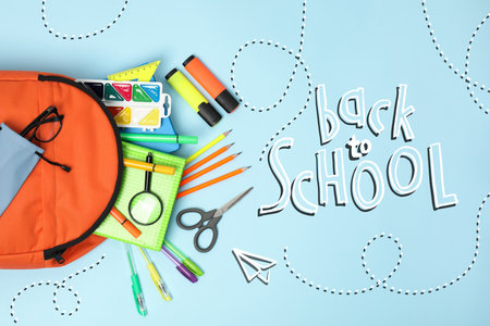 Backpack with stationery on light blue background, top view. Back to school
