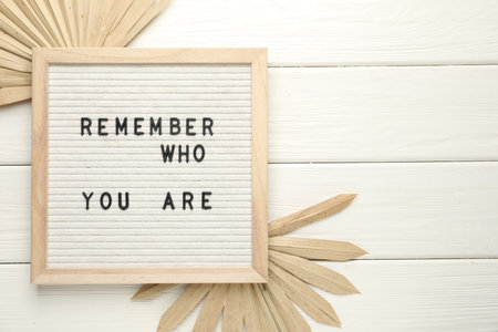 Letter board with phrase Remember Who You Are and decor elements on white wooden table, flat lay. Space for textの写真素材