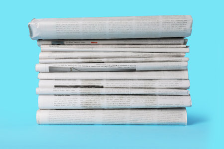 Stack of newspapers in different languages on light blue backgroundの写真素材