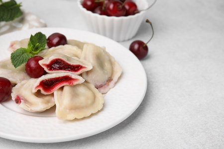 Traditional Ukrainian dumplings (varenyky) with cherries served on light table, closeupの写真素材