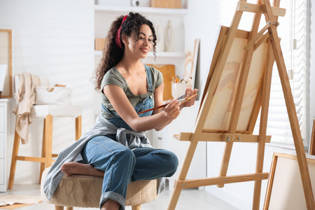 Smiling woman drawing picture on canvas in studioの写真素材