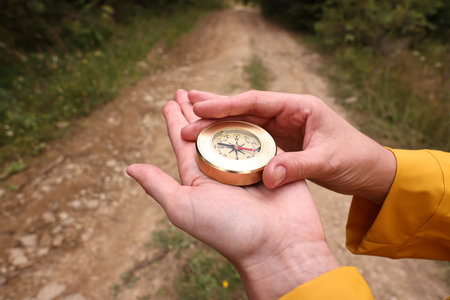 Woman holding compass near pathway outdoors, closeupの写真素材