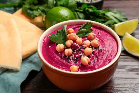 Tasty beetroot hummus in bowl and products on wooden table, closeupの写真素材