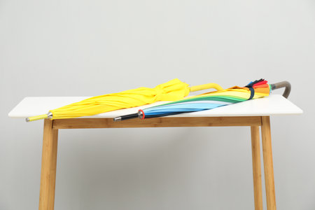 Colorful umbrellas on white table against light gray background