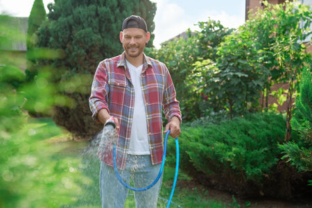 Man watering lawn with hose in backyardの写真素材