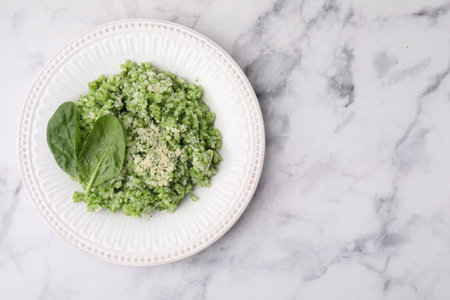 Tasty spinach risotto served on white marble table, top view. Space for text