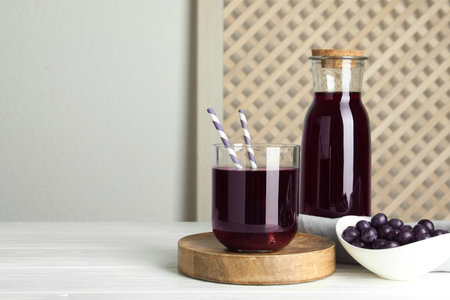 Delicious acai juice and berries on white wooden table. Space for textの写真素材