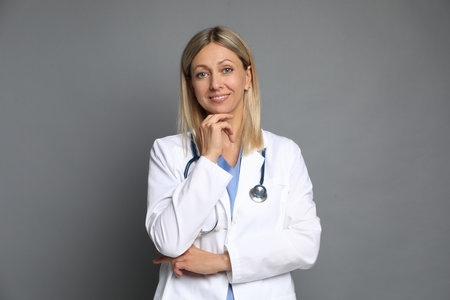 Portrait of doctor in medical uniform with stethoscope on grey backgroundの写真素材