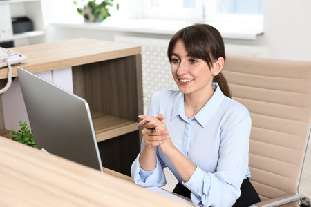 Professional receptionist working at wooden desk in officeの写真素材