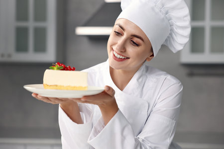 Professional chef with piece of delicious cheesecake in kitchenの写真素材