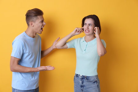 Emotional young couple arguing on orange backgroundの写真素材