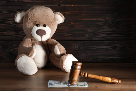 Alimony. Toy bear, gavel and dollar banknotes on wooden tableの写真素材