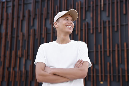 Portrait of smiling man in baseball cap near dark wall, low angle viewの写真素材