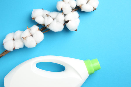 Bottle of laundry detergent and cotton flowers on blue background, flat layの写真素材